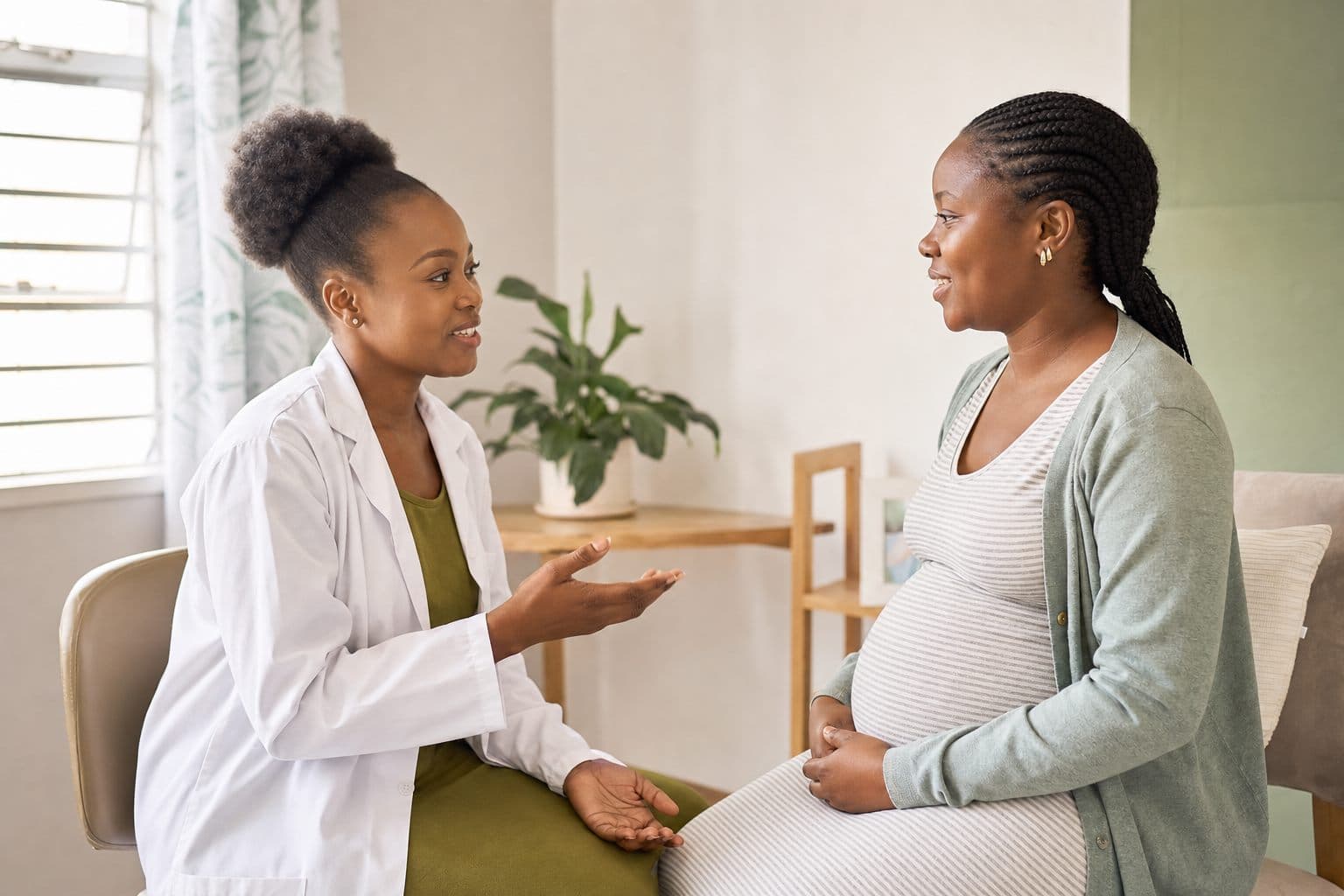 African clinician speaking warmly with a pregnant mother during antenatal care